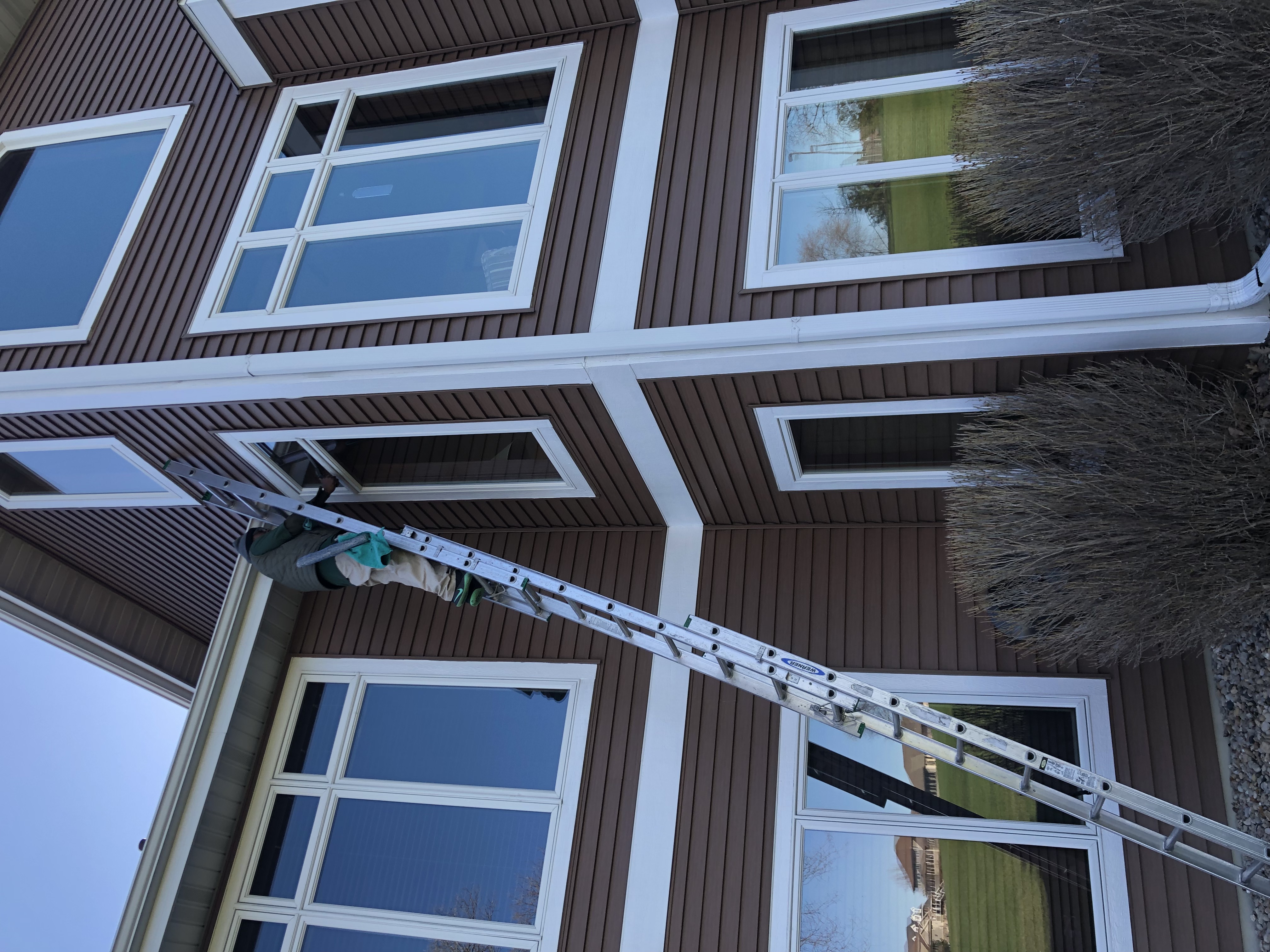 Technician cleaning exterior windows on residential home