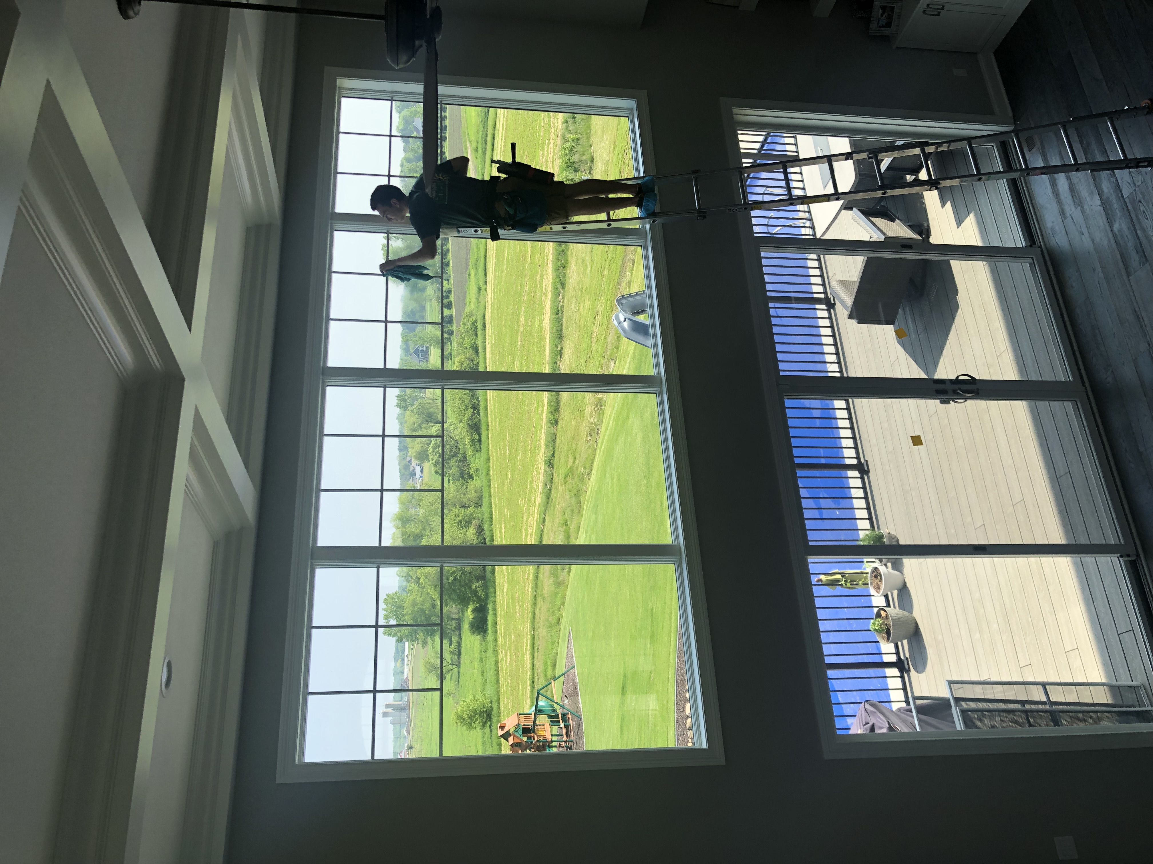 Technician cleaning large interior windows with deck view